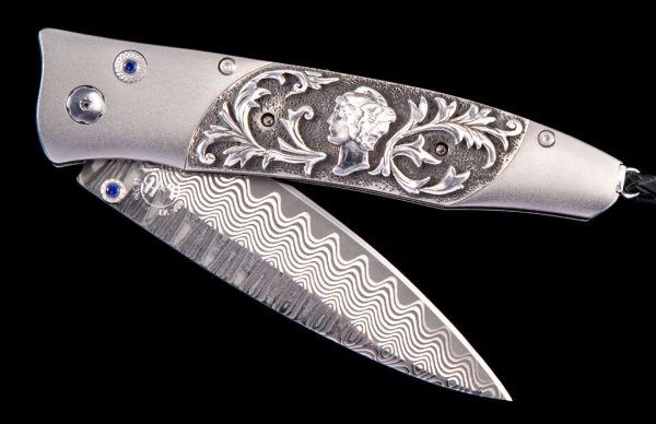 The Gentac ‘Quicksilver’ features a light and resilient frame in aerospace grade titanium, inlaid with hand-carved sterling silver by Lee Downey, with an authentic Mercury Dime minted from 1916-1945. The blade is 'Wave' damascus with ZDP-189 steel core; the one-hand button lock and the thumb stud are set with blazing blue sapphire gemstones.
An exceptional design that offers rigorous performance in a sleek, comfortable knife, the Gentac is also the perfect canvas to showcase William Henry’s range of exotic materials and techniques.
The ‘Quicksilver’ features the artistry, hi-tech, and hand-forged metals that are the hallmark of William Henry's collections; a distinctive personality statement to be worn and used for a lifetime.
Features & Specs
One-hand button lock system
Leather carrying case
Shipped in an elegant wood presentation box
Dimensions: 
Blade 3.25" (82.5mm)
Handle 3.80" (96.5mm)
Overall open 7.00" (177.8mm)
60 of 100