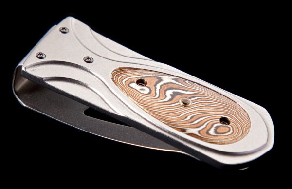 The Zurich ‘Twist’ features a frame in aerospace grade titanium, inlaid with hand-forged 'Twist' mokume gane by Mike Sakmar, and punctuated by a white topaz gemstone.
The clip is machined and blast-polished from tempered stainless steel, with a beautifulengraving bright cut against the matte-finished background. 
The ‘Twist’ money clip is a beautiful, and functional personality statement featuring some of the unique materials and forged metals that are the hallmark of William Henry's collections; a timeless heirloom to be proudly worn and used for a lifetime before handing it down to another generation.
Unique Material Info 
Features & Specs
Mechanism: tension
Engraved serial number