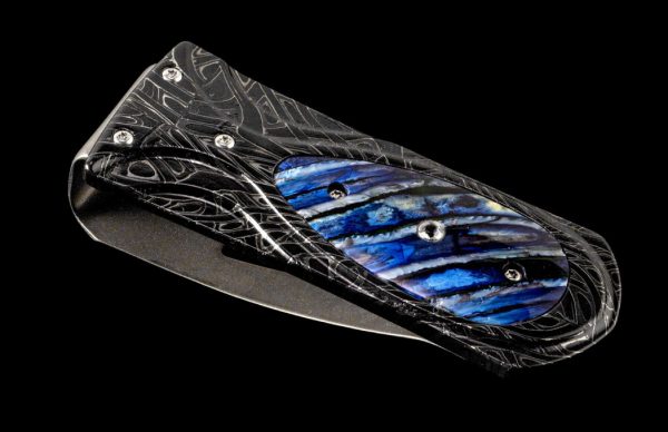 M3 ZURICH BLUE WAVE
EDITION 002 of 988 PIECES -
The Zurich ‘Blue Wave’ is a beautiful money clip featuring a frame in hand-forged 'Brain Wave' damascus by Chad Nichols, inlaid with blue 10,000 year-old fossil Woolly Mammoth tooth, and white topaz gemstone. 
FEATURES & SPECS
Mechanism: tension
Engraved serial number